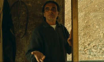 Movie still from “Taste of Cherry” (1997), directed by Abbas Kiarostami – A man standing in front of a window; Medium shot, Low angle
