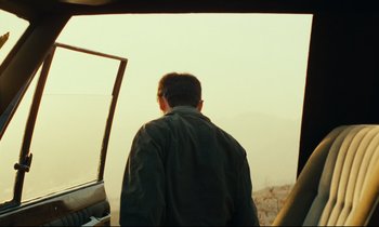 Movie still from “Taste of Cherry” (1997), directed by Abbas Kiarostami – A man standing next to a car looking out a window; Medium shot, Over the shoulder angle