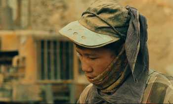 Movie still from “Taste of Cherry” (1997), directed by Abbas Kiarostami – A man wearing a hat and a neck scarf; Close Up shot, Low angle