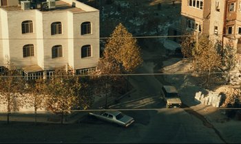 Movie still from “Taste of Cherry” (1997), directed by Abbas Kiarostami – An aerial view of a street with a car parked on the side of the road; Extreme Wide shot, High angle
