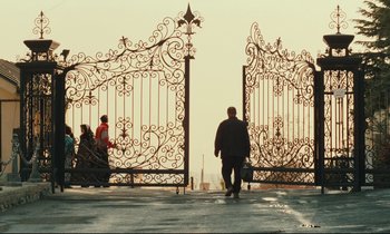 Movie still from “Taste of Cherry” (1997), directed by Abbas Kiarostami – A man is standing in front of a metal gate; Extreme Wide shot, Low angle