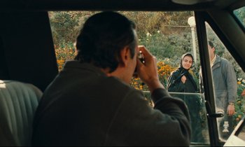 Movie still from “Taste of Cherry” (1997), directed by Abbas Kiarostami – A man taking a picture of a woman through a car window; Medium shot, Over the shoulder angle