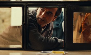 Movie still from “Taste of Cherry” (1997), directed by Abbas Kiarostami – A man is looking through a window at something on a table; Close Up shot, Over the shoulder angle