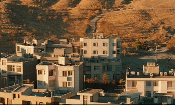 Movie still from “Taste of Cherry” (1997), directed by Abbas Kiarostami – A view of some buildings in the middle of a city; Extreme Wide shot, High angle