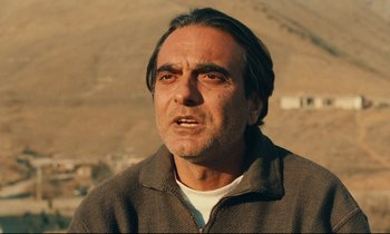 Movie still from “Taste of Cherry” (1997), directed by Abbas Kiarostami – A person wearing a jacket; Close Up shot, Over the shoulder angle