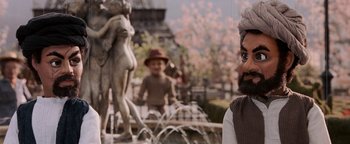 Movie still from “Team America: World Police” (2004), directed by Trey Parker – A man standing in front of a fountain with statues; Close Up shot, Over the shoulder angle