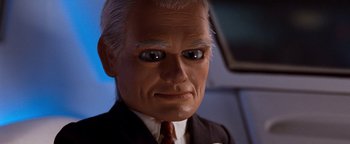 Movie still from “Team America: World Police” (2004), directed by Trey Parker – The head of a man in a suit and tie; Close Up shot, Low angle