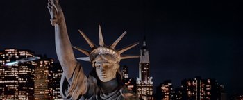 Movie still from “Team America: World Police” (2004), directed by Trey Parker – A statue of the statue of liberty in front of a city skyline at night; Wide shot, Low angle
