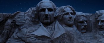Movie still from “Team America: World Police” (2004), directed by Trey Parker – View of the faces of two presidents on mount rushmore at night; Wide shot, Low angle