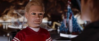 Movie still from “Team America: World Police” (2004), directed by Trey Parker – The face of a man with blonde hair; Close Up shot, Low angle