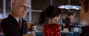 Movie still from “Team America: World Police” (2004), directed by Trey Parker – A woman in a red polka dot dress is holding a cup; Close Up shot, Over the shoulder angle