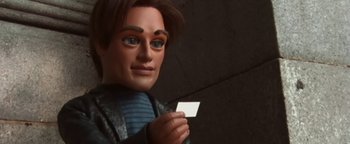 Movie still from “Team America: World Police” (2004), directed by Trey Parker – A man holding a piece of paper in front of a dark background; Close Up shot, Low angle