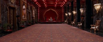 Movie still from “Team America: World Police” (2004), directed by Trey Parker – A large room with red walls and red carpet; Extreme Wide shot, High angle