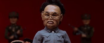 Movie still from “Team America: World Police” (2004), directed by Trey Parker – The face of a doll wearing glasses; Close Up shot, Low angle