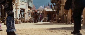 Movie still from “Team America: World Police” (2004), directed by Trey Parker – People are walking in an open air marketplace; Wide shot, Low angle