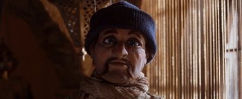 Movie still from “Team America: World Police” (2004), directed by Trey Parker – The face of a doll wearing a blue hat; Close Up shot, Low angle