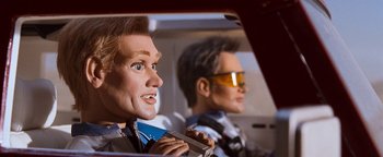 Movie still from “Team America: World Police” (2004), directed by Trey Parker – Two mannequins in a car wearing goggles; Close Up shot, Low angle