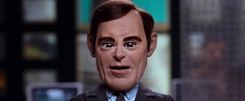 Movie still from “Team America: World Police” (2004), directed by Trey Parker – The face of a man wearing a suit and tie; Close Up shot, High angle