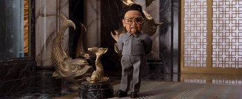 Movie still from “Team America: World Police” (2004), directed by Trey Parker – A statue of kim jong il in a room with a fish statue; Medium shot, Low angle