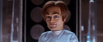 Movie still from “Team America: World Police” (2004), directed by Trey Parker – The face of a man with blue eyes and brown hair; Close Up shot, Low angle