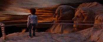Movie still from “Team America: World Police” (2004), directed by Trey Parker – A child standing in front of a large statue of a man's face; Wide shot, Low angle