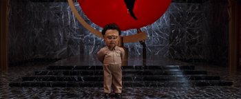 Movie still from “Team America: World Police” (2004), directed by Trey Parker – A man standing in front of a giant red ball; Wide shot, Low angle