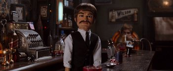 Movie still from “Team America: World Police” (2004), directed by Trey Parker – A man in a suit and tie standing at a bar; Close Up shot, High angle