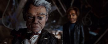 Movie still from “Team America: World Police” (2004), directed by Trey Parker – A man's face and a man's head; Close Up shot, Low angle