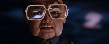 Movie still from “Team America: World Police” (2004), directed by Trey Parker – A person's face wearing glasses; Close Up shot, Low angle