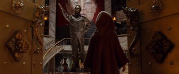 Movie still from “Team America: World Police” (2004), directed by Trey Parker – A statue of mao zedong is shown in front of a staircase; Wide shot, Over the shoulder angle