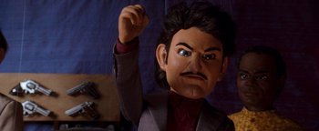 Movie still from “Team America: World Police” (2004), directed by Trey Parker – The head of a man in a business suit; Close Up shot, Low angle