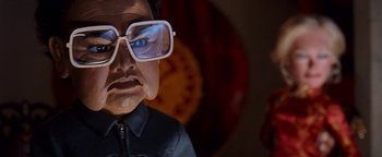 Movie still from “Team America: World Police” (2004), directed by Trey Parker – A person's face wearing glasses; Close Up shot, Low angle