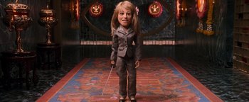 Movie still from “Team America: World Police” (2004), directed by Trey Parker – A woman in a suit holding a sword in a room; Medium shot, High angle