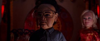 Movie still from “Team America: World Police” (2004), directed by Trey Parker – The face of a doll wearing glasses; Close Up shot, Low angle