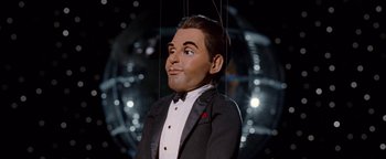 Movie still from “Team America: World Police” (2004), directed by Trey Parker – A marionette of a man wearing a tuxedo; Close Up shot, High angle