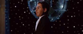 Movie still from “Team America: World Police” (2004), directed by Trey Parker – A man in a suit and bow tie is standing in front of a mirror; Close Up shot, Low angle
