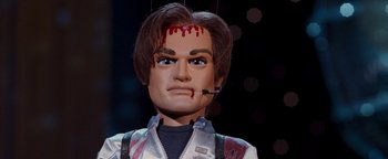 Movie still from “Team America: World Police” (2004), directed by Trey Parker – A marionette of a man with blood on his face; Close Up shot, Low angle