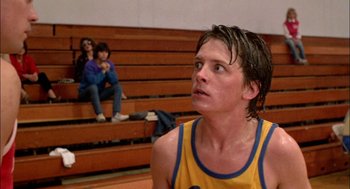 Movie still from “Teen Wolf” (1985), directed by Rod Daniel – A man in a yellow and blue tank top is looking up; Close Up shot, Over the shoulder angle