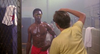 Movie still from “Teen Wolf” (1985), directed by Rod Daniel – A man in a yellow shirt and red shorts is standing in front of another man in a yellow shirt and red shorts; Medium shot, Over the shoulder angle