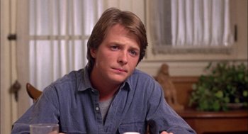 Movie still from “Teen Wolf” (1985), directed by Rod Daniel – A man sitting at a table with a cup in his hand; Close Up shot, Low angle