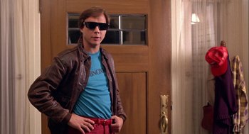 Movie still from “Teen Wolf” (1985), directed by Rod Daniel – A man in sunglasses standing in front of a door; Medium shot, Low angle