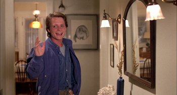 Movie still from “Teen Wolf” (1985), directed by Rod Daniel – A man standing in front of a mirror in a room; Medium shot, Over the shoulder angle