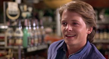 Movie still from “Teen Wolf” (1985), directed by Rod Daniel – A young man smiling for the camera in a bar; Close Up shot, Over the shoulder angle