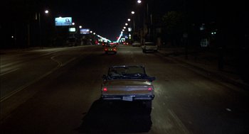 Movie still from “Teen Wolf” (1985), directed by Rod Daniel – A car driving down a street at night; Extreme Wide shot, High angle
