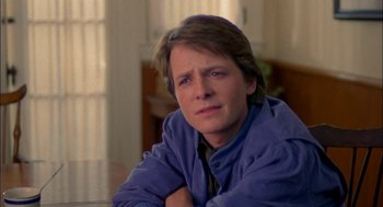 Movie still from “Teen Wolf” (1985), directed by Rod Daniel – A man sitting at a table with his arms crossed; Close Up shot, Over the shoulder angle