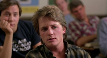 Movie still from “Teen Wolf” (1985), directed by Rod Daniel – A young man with long blonde hair wearing a plaid shirt; Close Up shot, Over the shoulder angle
