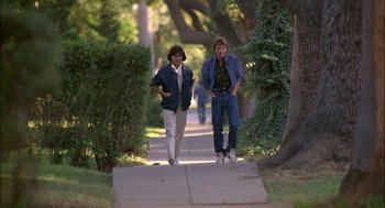 Movie still from “Teen Wolf” (1985), directed by Rod Daniel – Two people walking down a sidewalk near some trees; Wide shot, Low angle