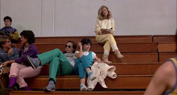 Movie still from “Teen Wolf” (1985), directed by Rod Daniel – A man and two women sitting on top of a wooden staircase; Wide shot, Low angle
