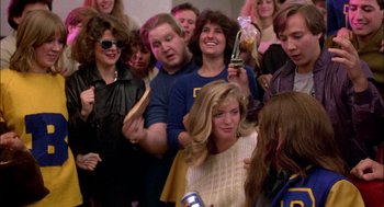 Movie still from “Teen Wolf” (1985), directed by Rod Daniel – A group of people standing around a woman; Medium shot, Over the shoulder angle