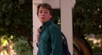 Movie still from “Teen Wolf” (1985), directed by Rod Daniel – A young man standing next to a tree with a blue backpack; Close Up shot, Low angle